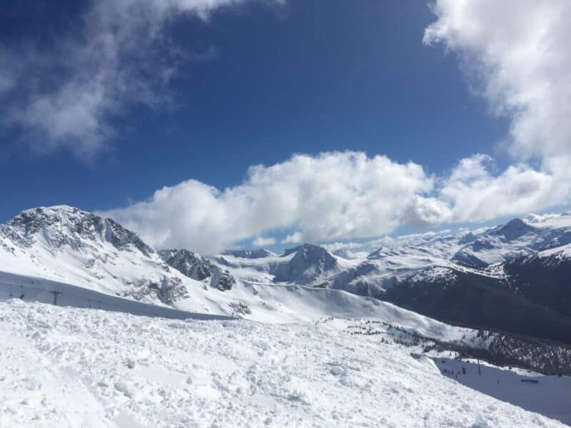 Snowy ski slope framed by white mountains and blue sky