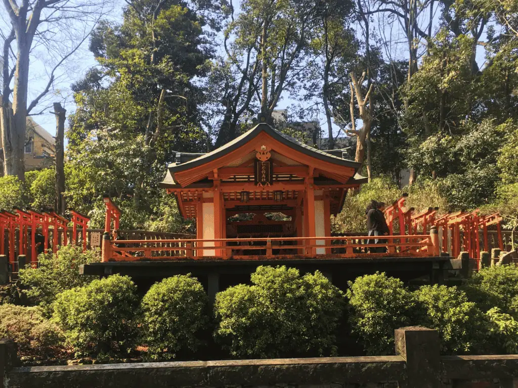 A japanese shrine is set against a lush green backdrop